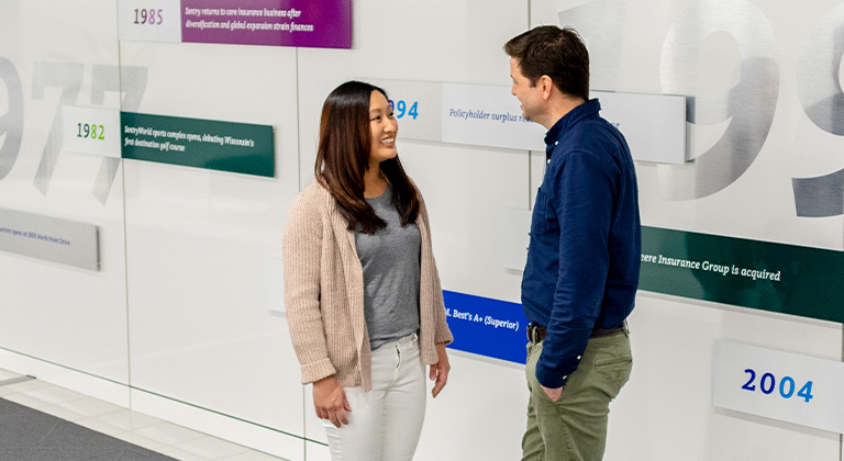 Two associates having a conversation near the timeline wall at Sentry home office in Stevens Point.