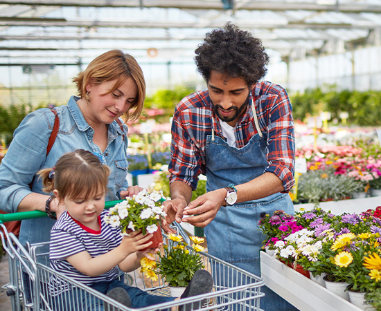 Girl sitting in a cart purchasing flowers with her mom