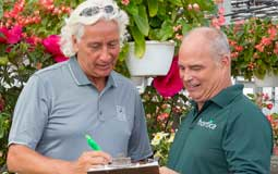 Two men talking while looking at a clipboard