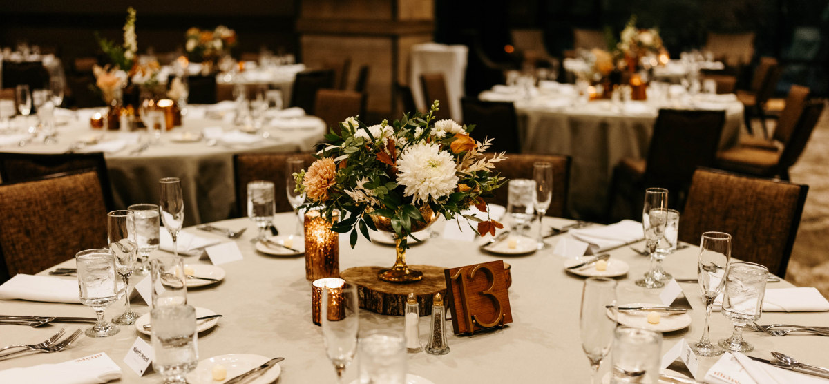 Elegant event table set with floral centerpiece, glowing candles, and table number 13.