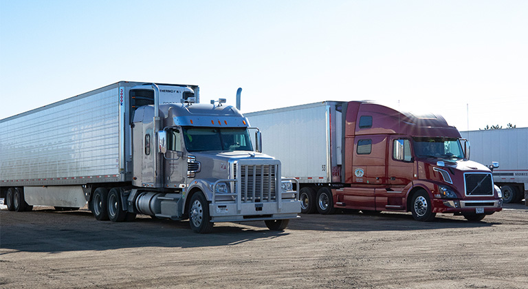 Two semi trucks parked in a lot.