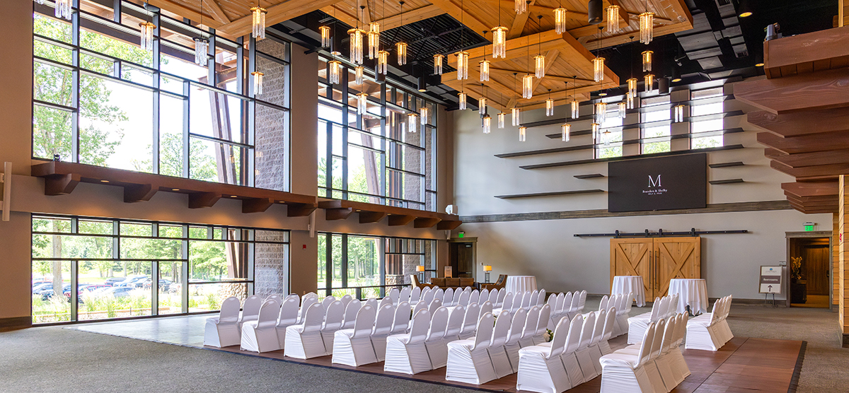 carousel-wedding-venue-atrium-3-1200x556 Atrium room set up for a wedding with white chairs facing a wall of windows.