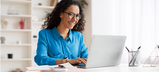 Woman smiling and typing on a laptop computer