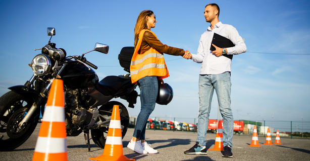Instructor and student shake hands before a motorcycle safety lesson