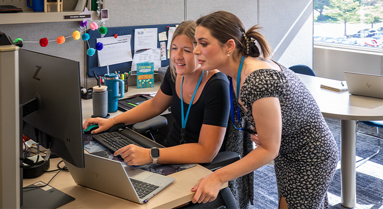 Two women looking at a computer and working together at a Sentry office