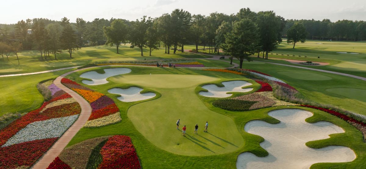 Hole 16 of the SentryWorld golf course from above showing four golfers on the green.
