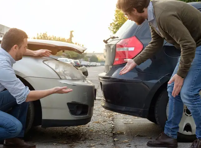 two people inspecting damage after an accident