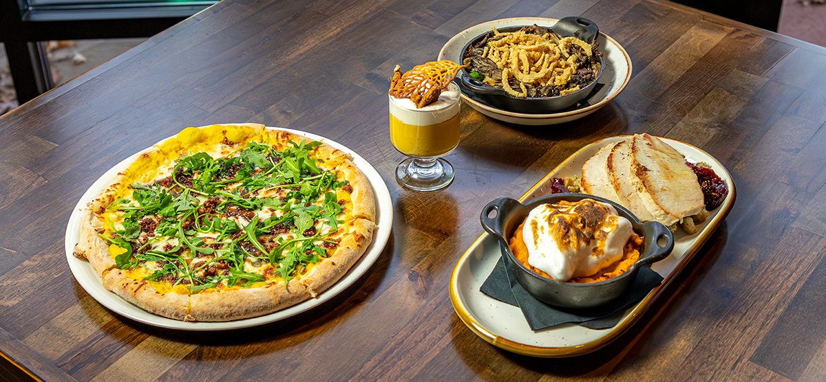 Plates of Thanksgiving themed food on a wood table. 