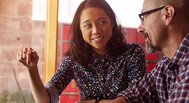 Woman pointing at laptop in meeting with man