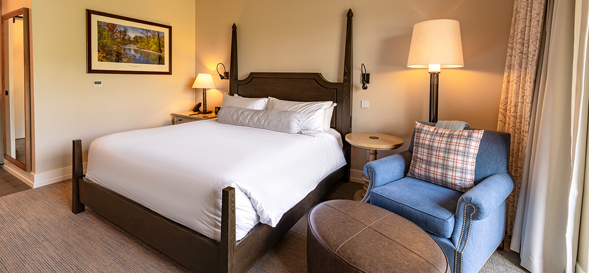 carousel-suite-golf-view-king-queen-2-1200x556 King bed with chair and ottoman.