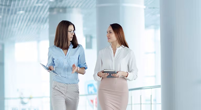 Two business people walking and meeting in an office