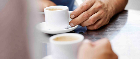 Close up of two peoples hands meeting over coffee