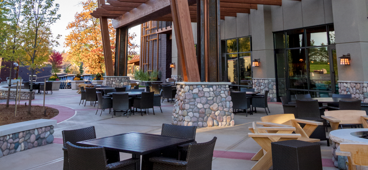 Outdoor patio with various seating arrangements and fall foliage around a building.