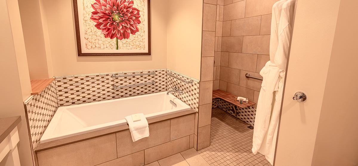 carousel-accessible-golf-view-executive-junior-suite-5-1200x556 Bathroom tub and shower with bench and grab bars.