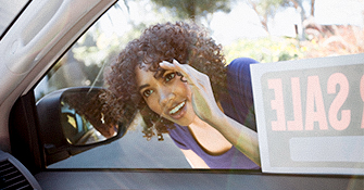 Woman looking into a car with a For Sale sign in the window