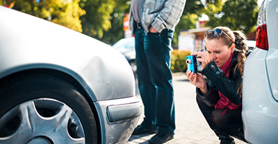 Man talking on phone and woman taking photograph of car