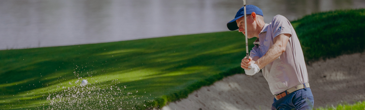 Male golfer hitting his ball out of a sand trap.