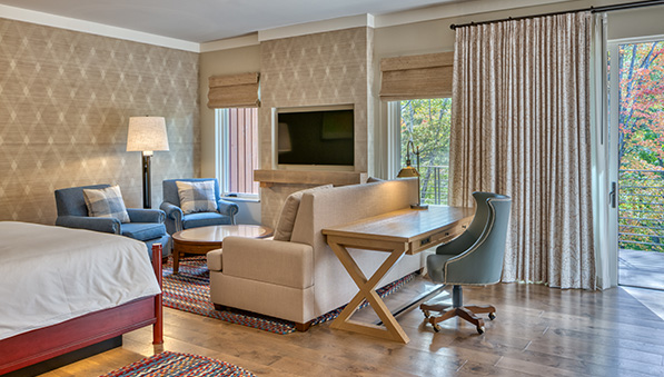 A suite at The Inn sitting area in front of a TV and fireplace. 