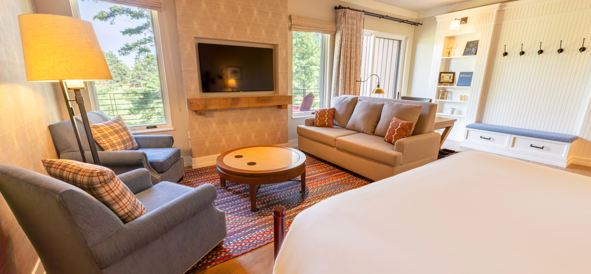 Seating area with a couch and two chairs in front of a king size bed. 