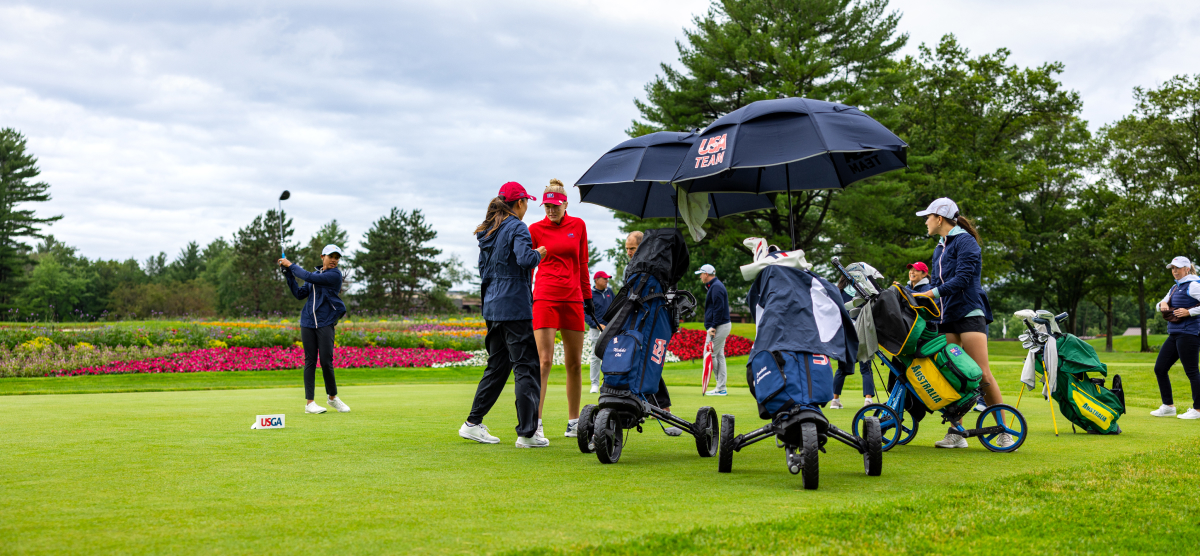 Golfers at SentryWorld with golf bags and umbrellas.