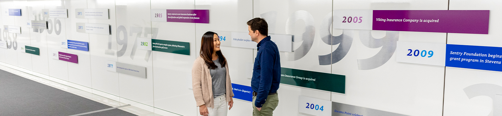 Two associates having a conversation near the timeline wall at Sentry home office in Stevens Point.