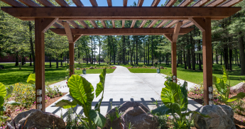Wooden pergola framing a paved path toward SentryWorld.