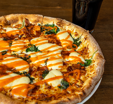 Pizza next to a dark colored beer. 
