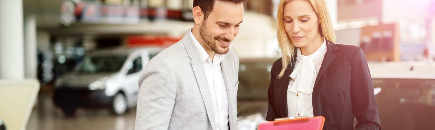 Two people looking at paperwork in dealership.