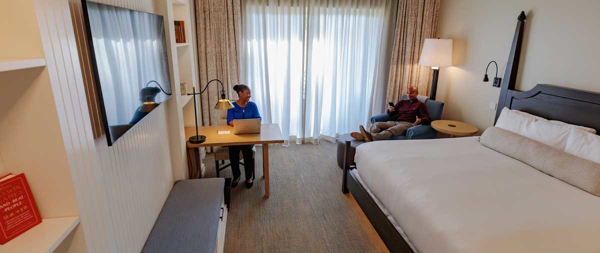 Two guests enjoying the desk and lounge chair area in their King Terrace room at The Inn