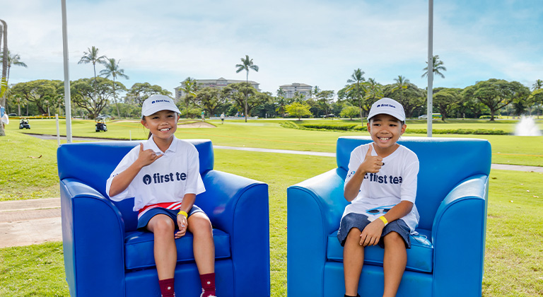 Two happy First Tee kids seated in armchairs on golf course