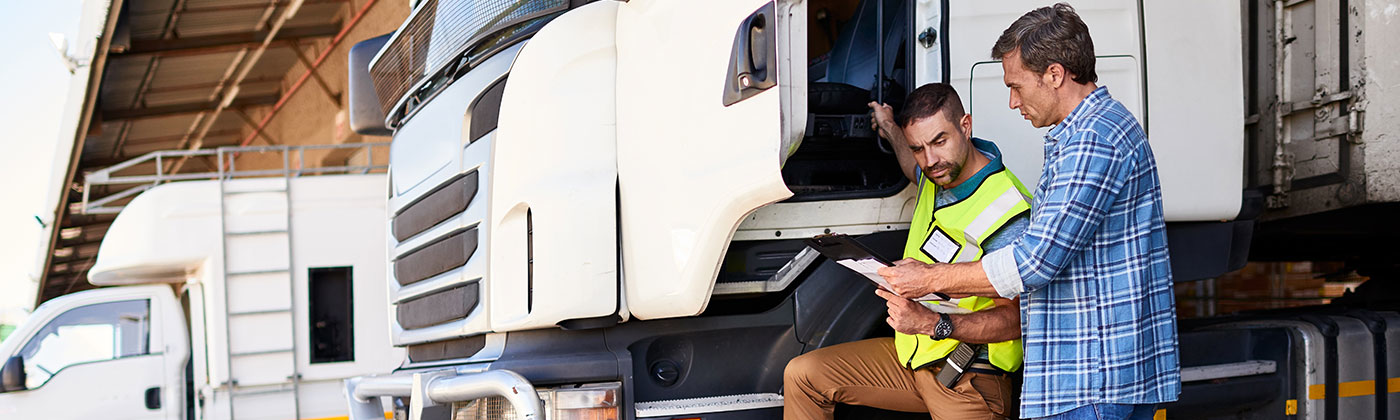 Semi trailer truck driver talking to coworker outside truck