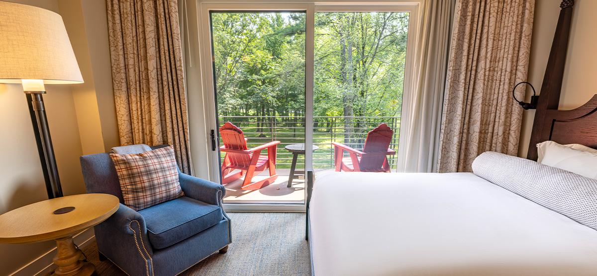 carousel-queen-terrace-2-1200x556 Queen bed and chair in front of a terrace overlooking the golf course.