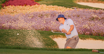 Man hitting his golf ball out of a sand trap on the 16th hole at SentryWorld.