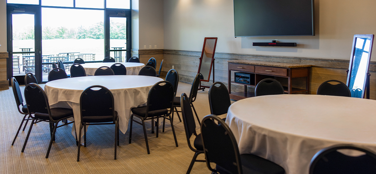 carousel-wedding-venue-community-room-1-1200x556 Room with three round tables with chairs.