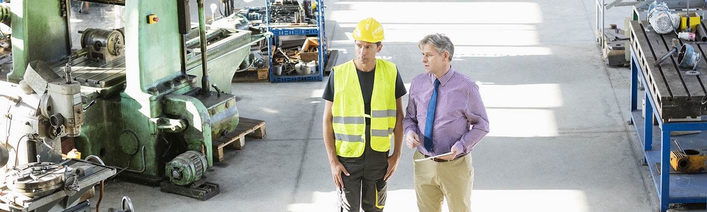 Business man consulting factory worker in hard hat