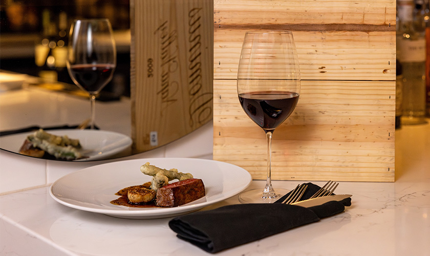 Wine glass next to a plated steak dinner