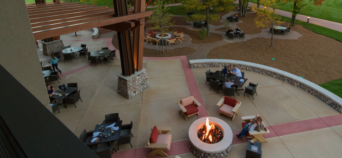 Overhead view of an outdoor patio with dining tables, lounge chairs, and a lit fire pit.