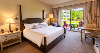 info-card-luxury-room-345x182 Hotel room with one king bed and patio door to outside.