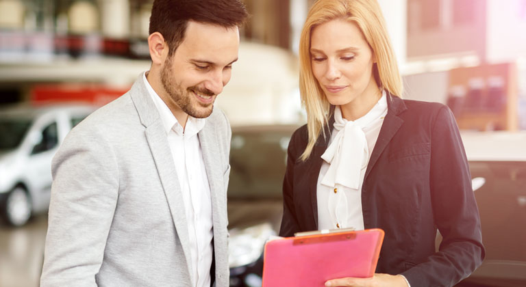 Two people looking at paperwork in dealership.