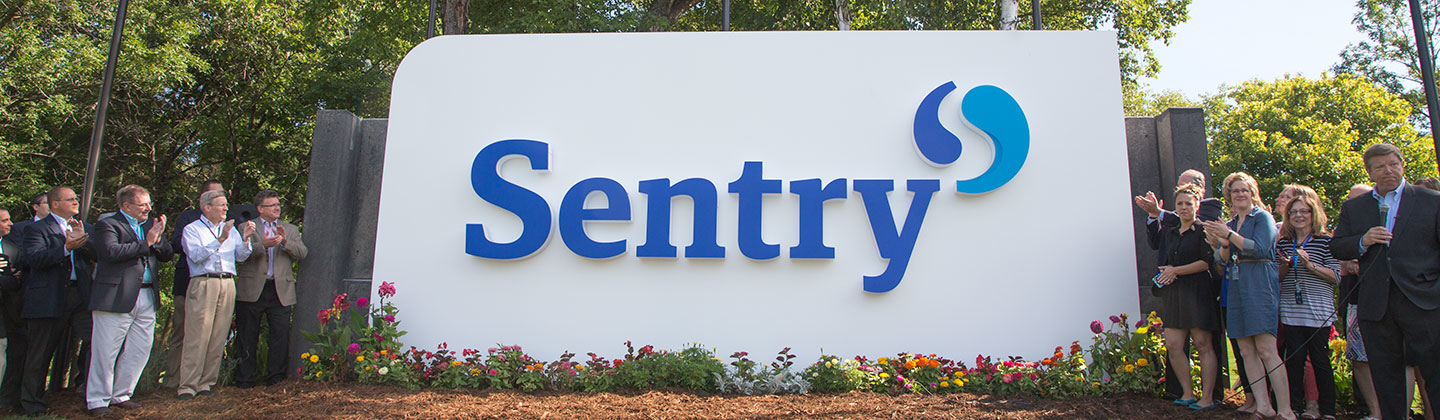 Sentry employees standing by Sentry sign