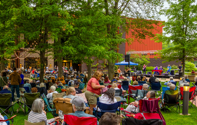 Outdoor concert at SentryWorld with a band performing for a seated audience on a grassy lawn.