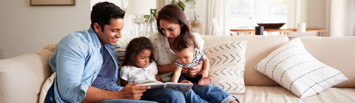 Family of four reading a children's book