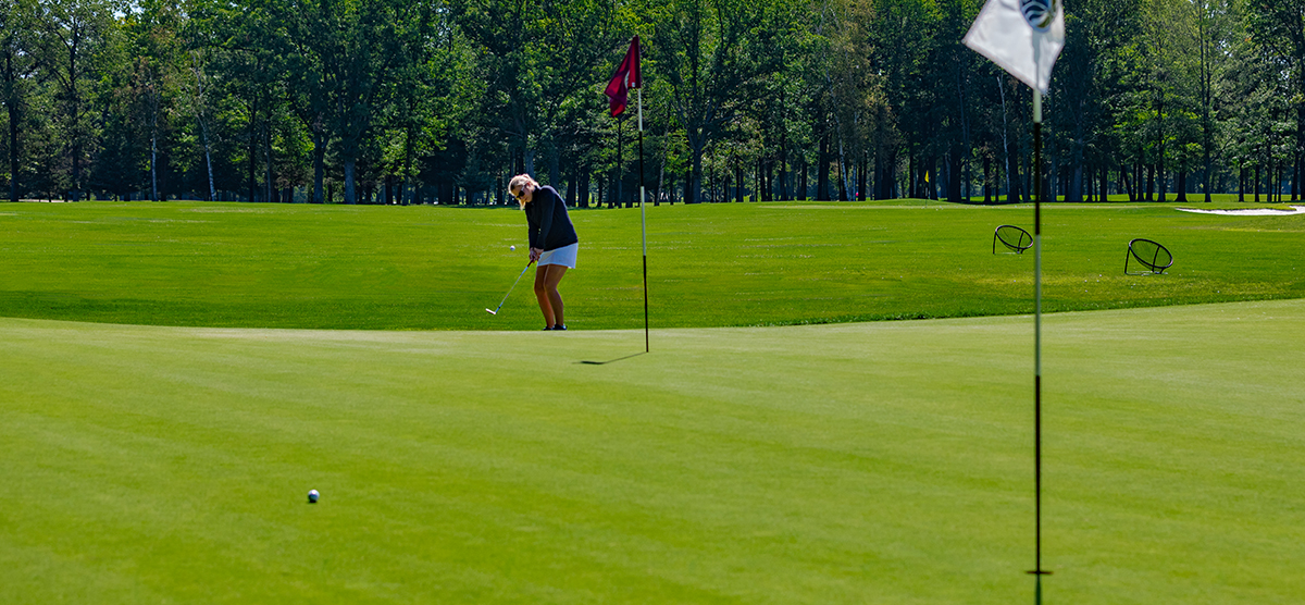 Player chipping onto the practice green at the SentryWorld golf course