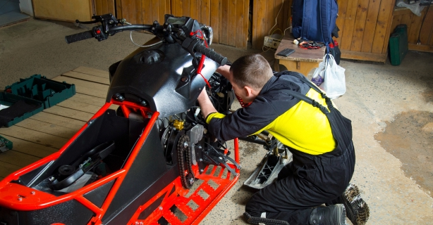 Person performing maintenance on snowmobile
