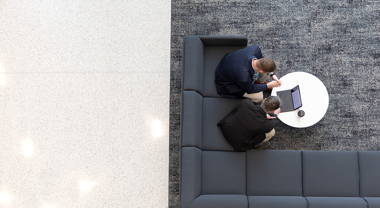 two men sitting on couch working on laptop