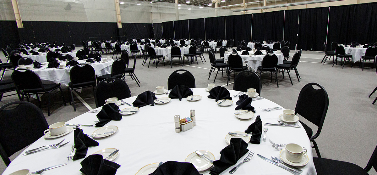 Round tables set for dining in the fieldhouse at SentryWorld