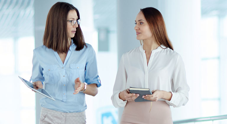 Two business women walking and talking