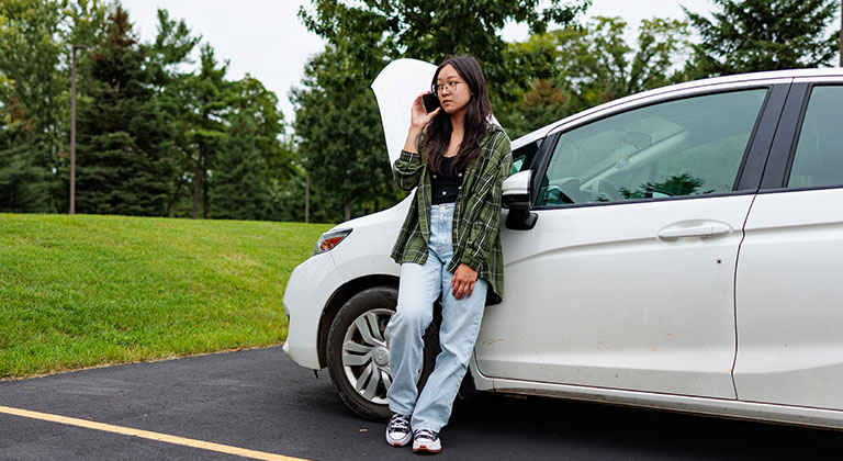 Young woman making a call after experiencing car trouble.