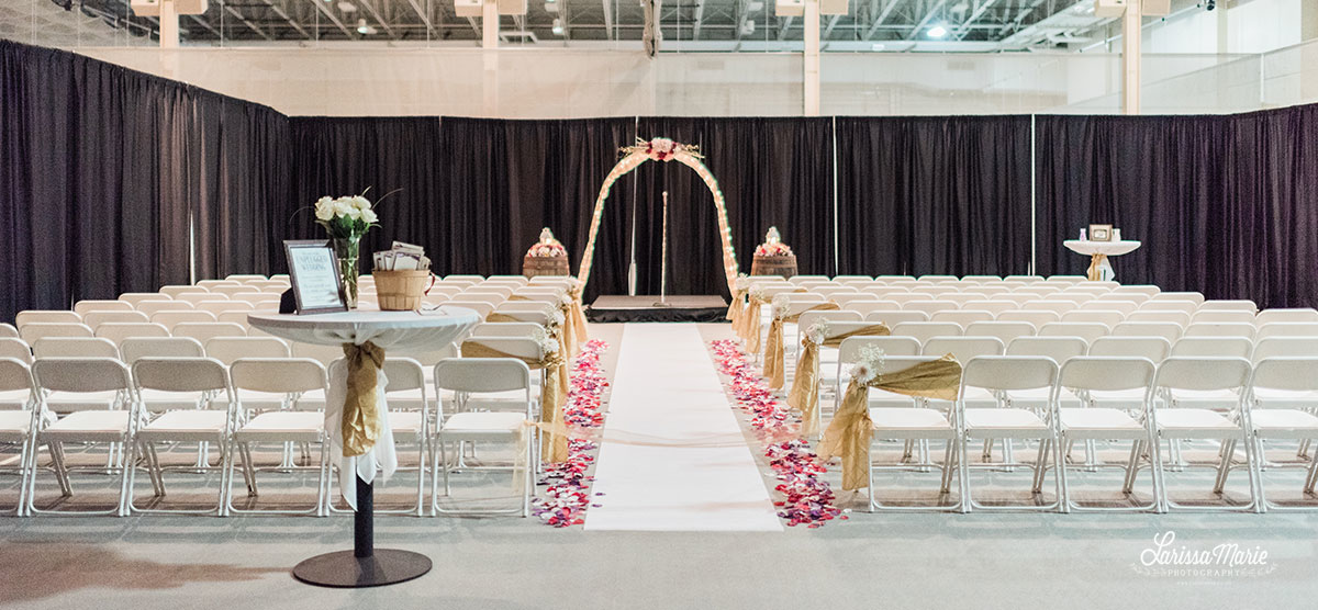 Rows of chairs and an arch for a wedding ceremony in the SentryWorld fieldhouse