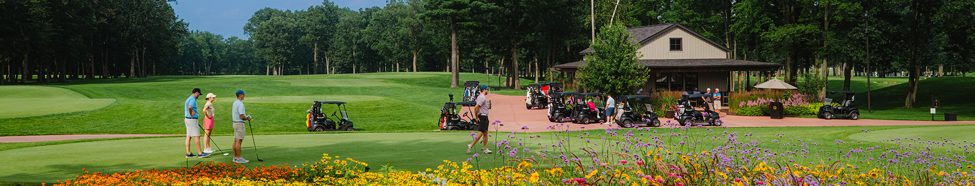 hero-tee-times-rates-1900x364 Golfers and golf carts at the refreshment station building.